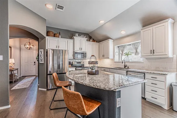 a kitchen with kitchen island granite countertop a sink stove and refrigerator