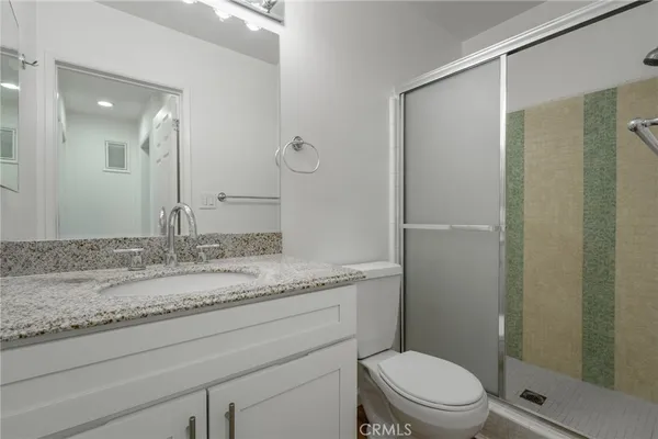 a bathroom with a granite countertop sink toilet and shower