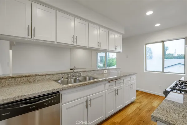 a kitchen with granite countertop white cabinets and a sink