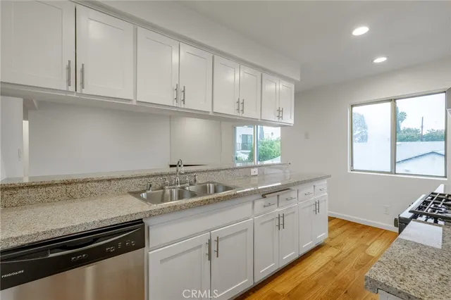 a kitchen with granite countertop white cabinets and a sink