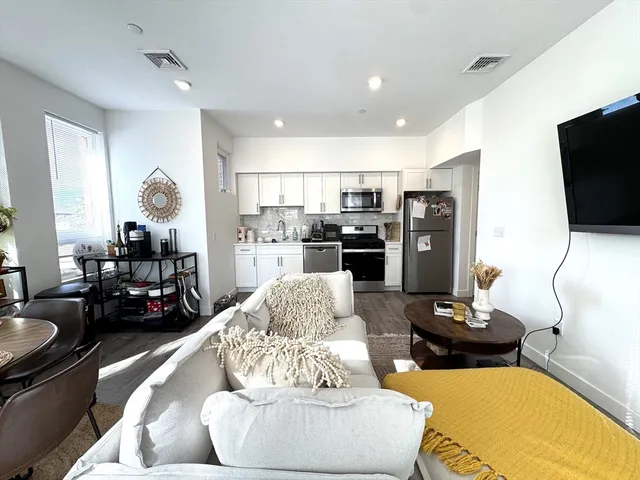 a living room with stainless steel appliances furniture and a flat screen tv