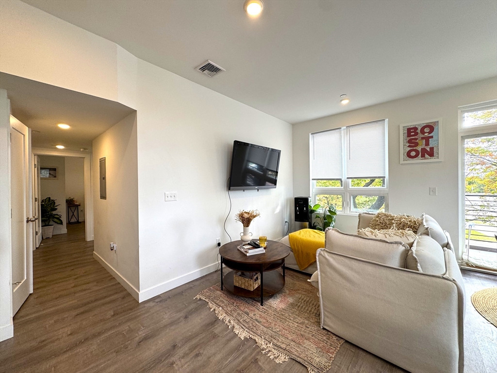 302 Broadway, Unit 303 Everett, MA 02149 - Photo 4 of 11 a living room with furniture and a flat screen tv