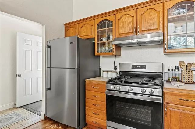 a kitchen with stainless steel appliances granite countertop a stove top oven a refrigerator a sink and dishwasher with wooden floor