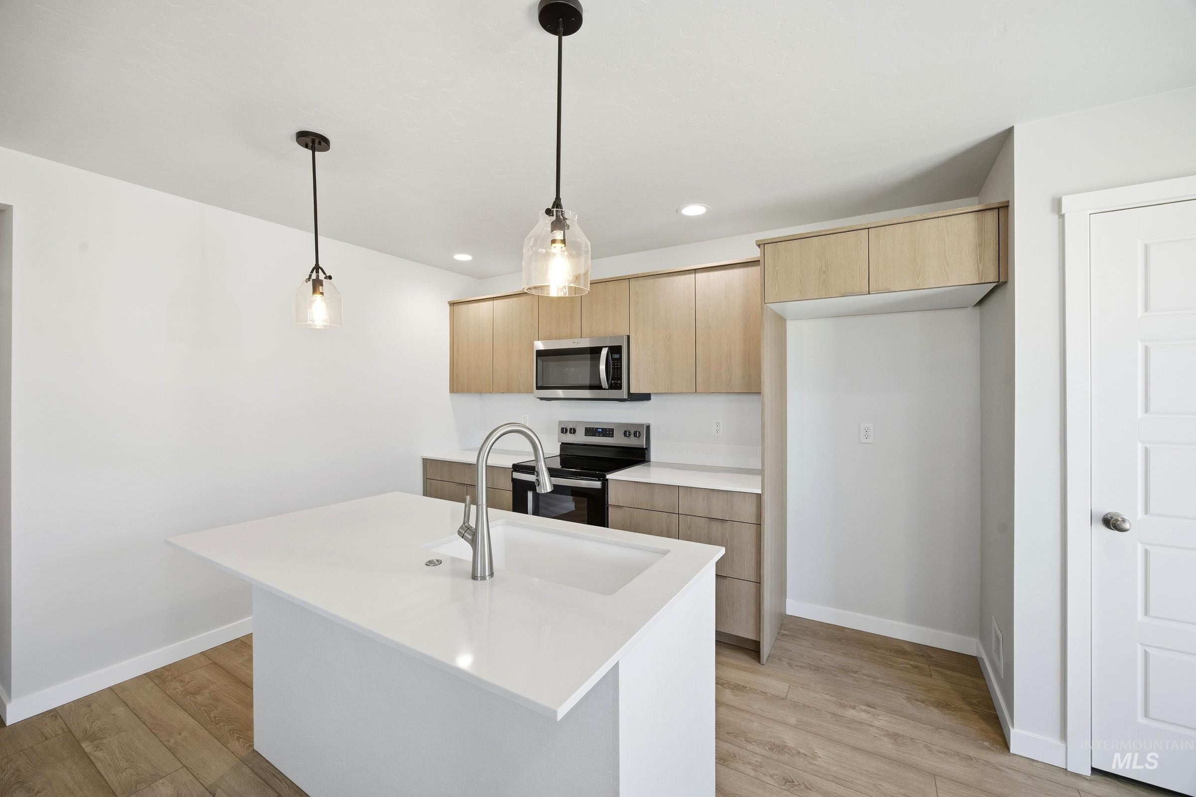 16211 Andes Avenue Caldwell, ID 83607 - Photo 4 of 22 Kitchen featuring wood-finish flooring, white countertops, built-in microwave, and pendant lighting