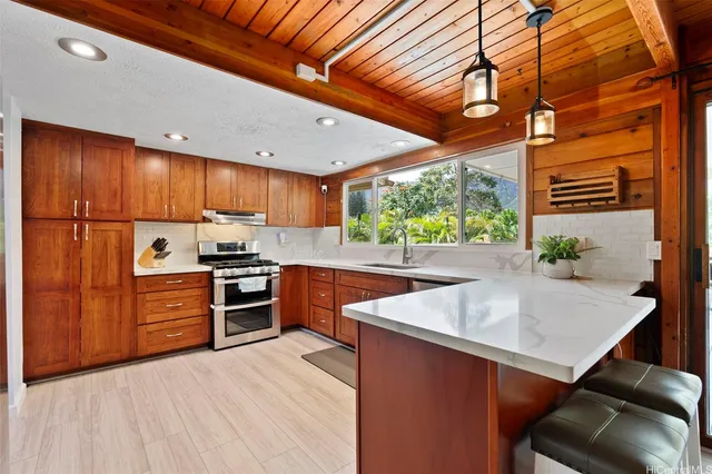 a kitchen with stainless steel appliances kitchen island granite countertop a sink a stove and a refrigerator