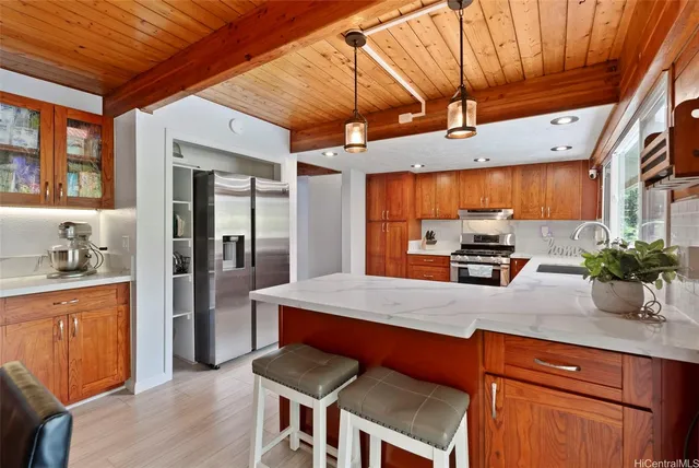 a kitchen with stainless steel appliances kitchen island granite countertop a table chairs in it and wooden floors