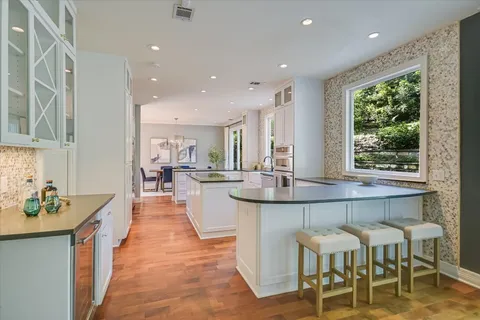 a dining hall with stainless steel appliances granite countertop a table and chairs in it