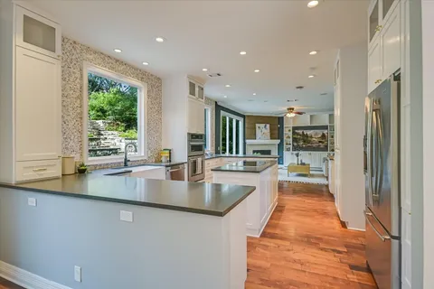 a large kitchen with stainless steel appliances a large counter top a stove a chimney a sink and a large window