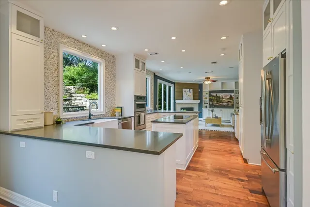 a large kitchen with stainless steel appliances a large counter top a stove a chimney a sink and a large window