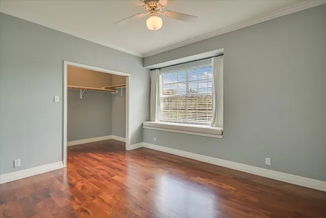 an empty room with wooden floor chandelier fan and windows