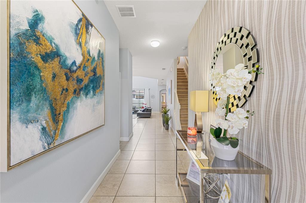 9006 Majesty Palm Road Kissimmee, FL 34747 - Photo 5 of 56 a hallway with painting on the wall and a large mirror