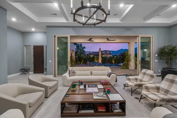 a living room with patio furniture and a chandelier