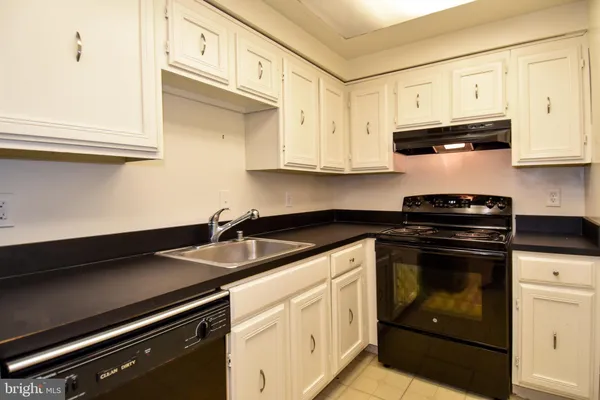 a kitchen with granite countertop white cabinets and black appliances