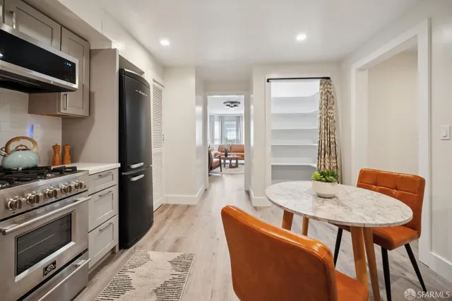 a kitchen with stainless steel appliances kitchen island granite countertop a table chairs stove and refrigerator