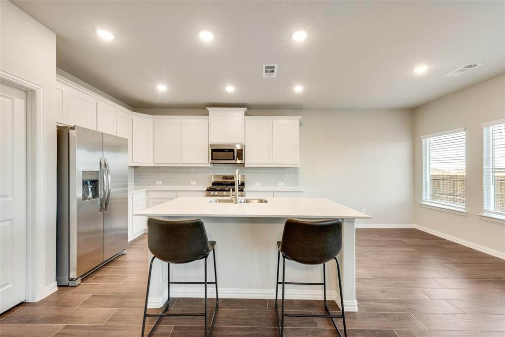 280 Sutter Mill Road Saginaw, TX 76131 - Photo 9 of 21 a kitchen with stainless steel appliances kitchen island granite countertop a kitchen island and chairs in it
