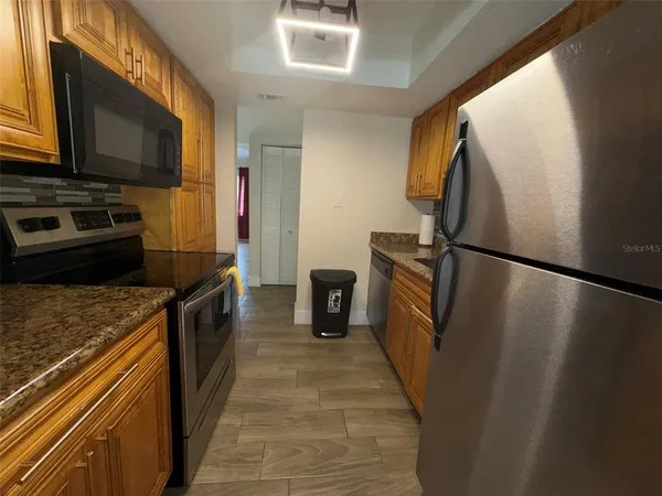 a kitchen with granite countertop a refrigerator and a stove top oven