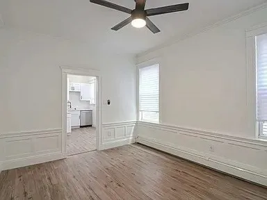 an empty room with wooden floor cabinet and windows