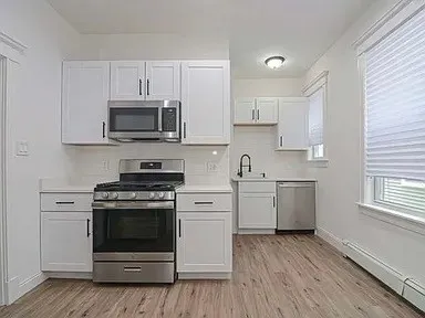 a kitchen with cabinets stainless steel appliances and wooden floor