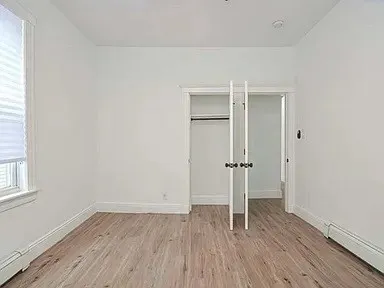 an empty room with wooden floor & window