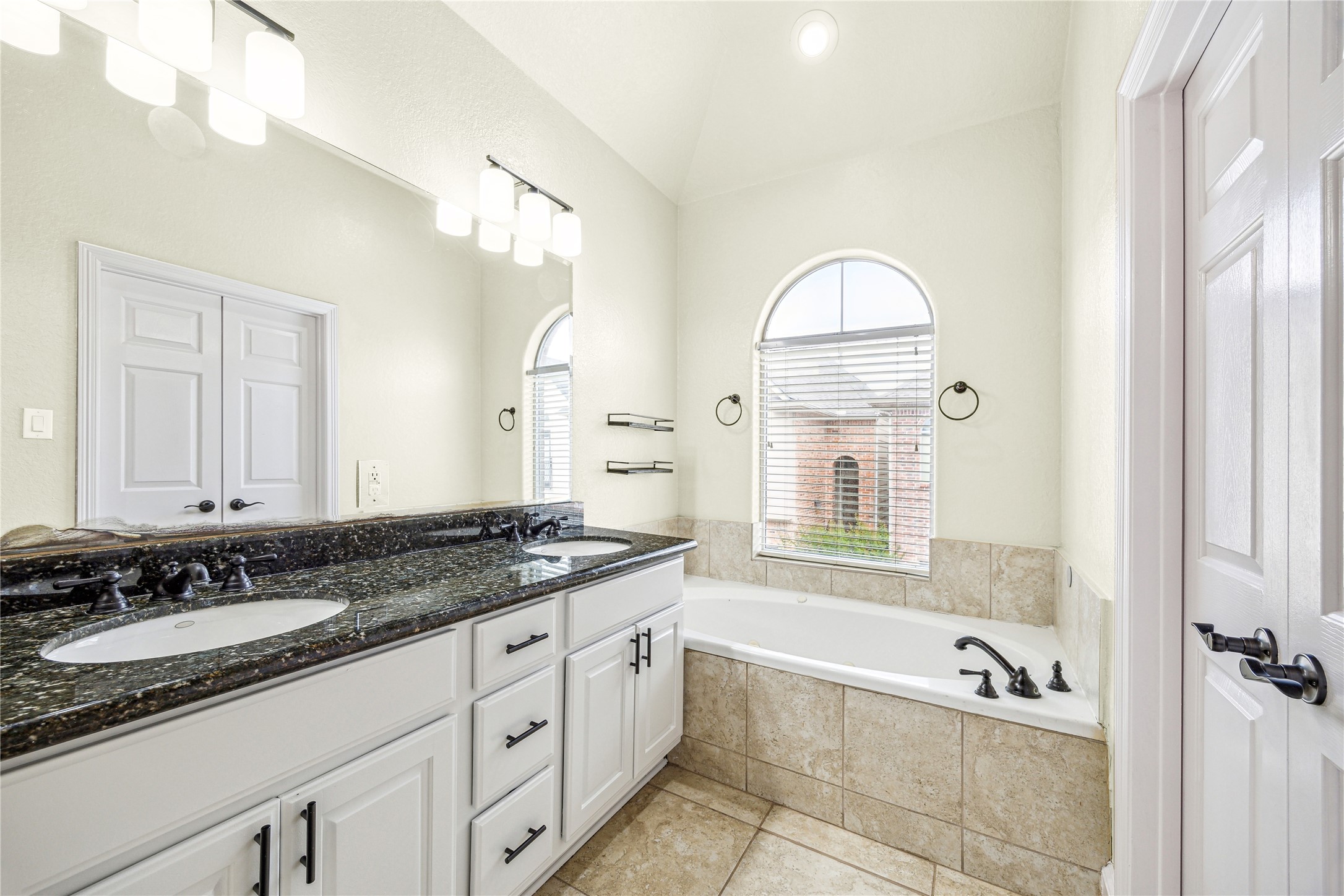 210 Grove Street Houston, TX 77020 - Photo 15 of 28 a bathroom with a granite countertop tub a double vanity sink and a mirror