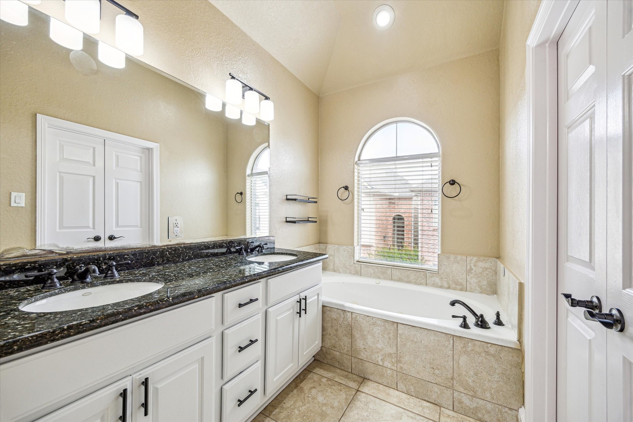 210 Grove Street Houston, TX 77020 - Photo 16 of 28 a bathroom with a granite countertop tub a double vanity sink and a mirror
