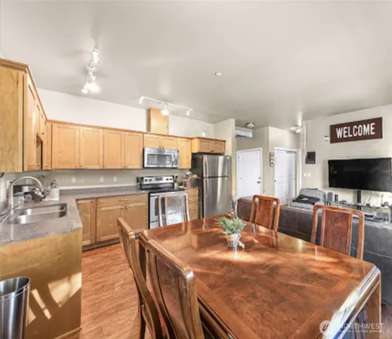 a kitchen with stainless steel appliances kitchen island granite countertop a table chairs and a refrigerator