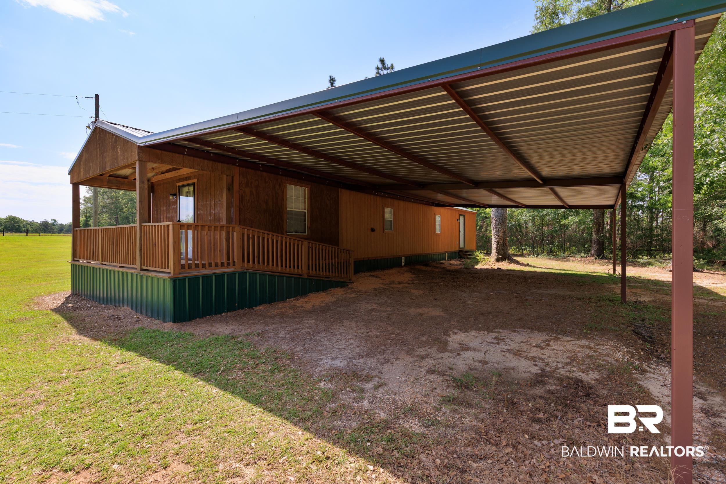 6725 Upper Creek Road Flomaton, AL 36441 - Photo 25 of 61 View of side of home featuring a carport, a yard, and covered porch