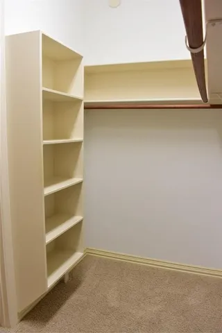 an empty room with a chandelier fan and wooden floor