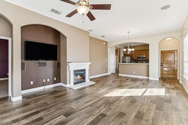 an empty room with windows fireplace and fans