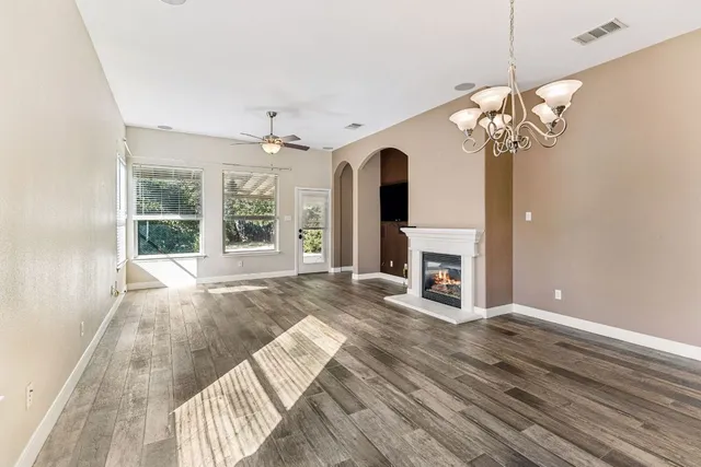 a view of a livingroom with a fireplace a chandelier and wooden floor