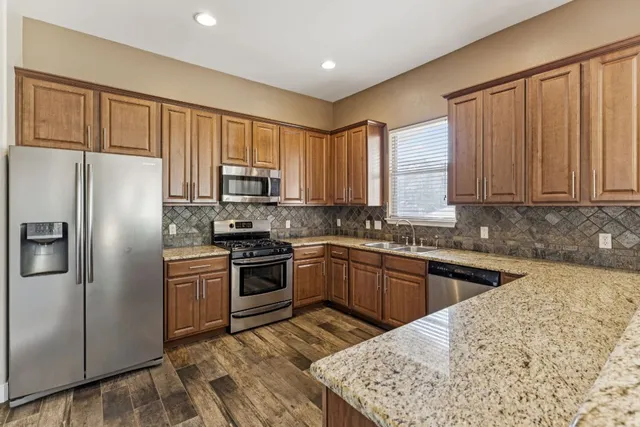 a kitchen with granite countertop wooden cabinets a refrigerator and a sink