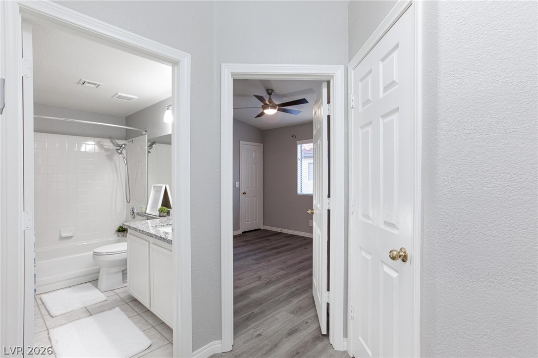 2254 Ramsgate Drive Henderson, NV 89074 - Photo 13 of 43 Clean lines define this bright bathroom with a shower-tub combo and sleek vanity, adjacent to a room with wood-look flooring.