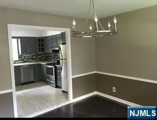 a view of kitchen and empty room with wooden floor