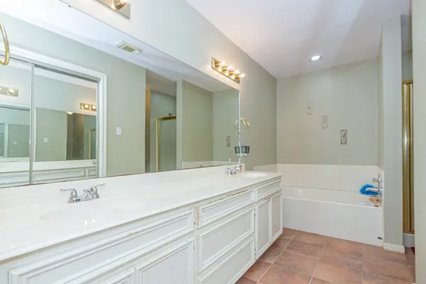 a bathroom with a sink double vanity granite tub shower and a mirror