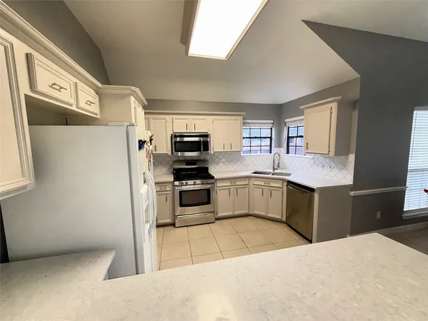 a kitchen with stainless steel appliances kitchen island granite countertop a refrigerator and a stove top oven