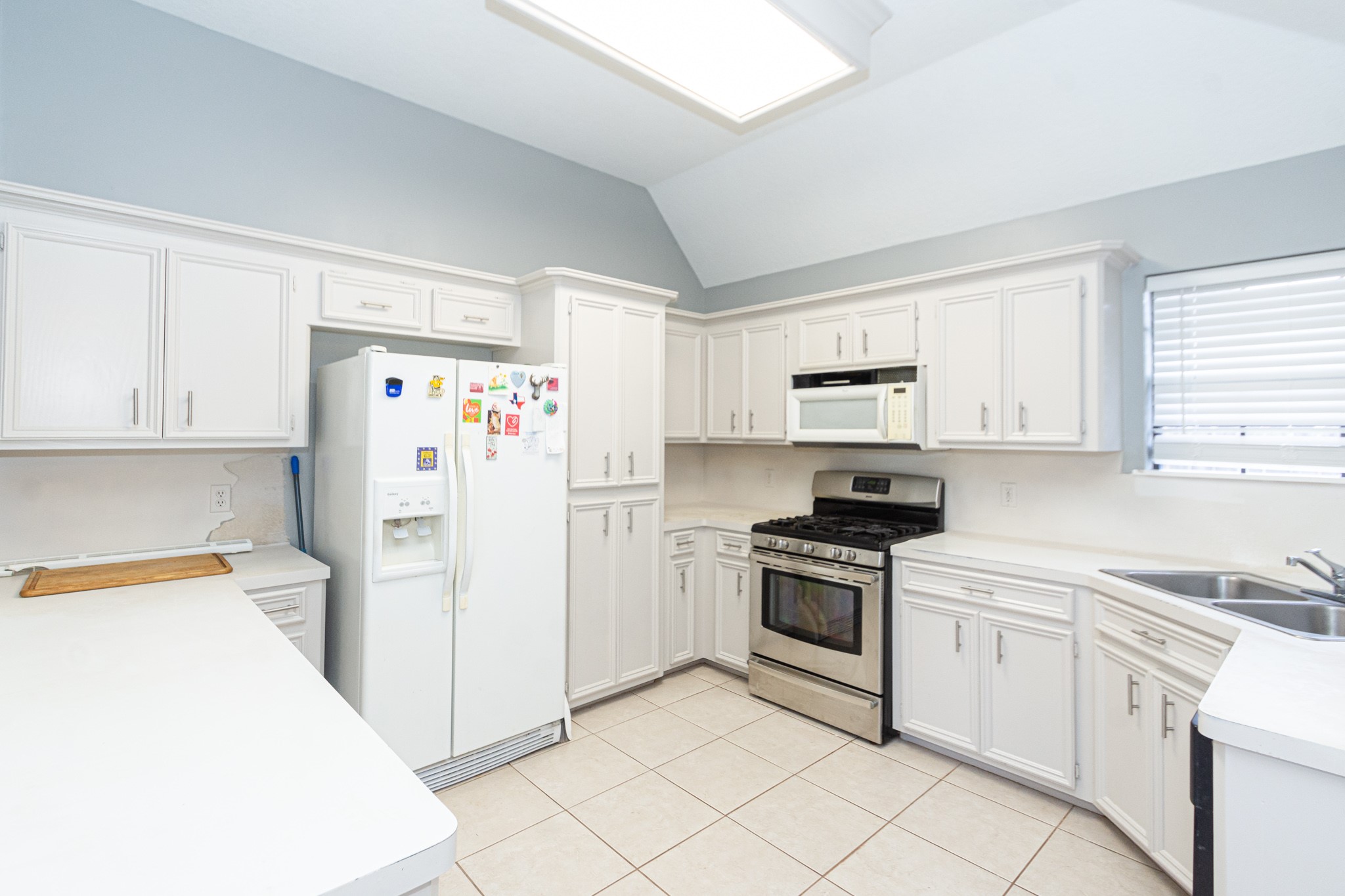 808 Manor Drive Angleton, TX 77515 - Photo 9 of 31 a kitchen with a refrigerator a stove top oven and white cabinets