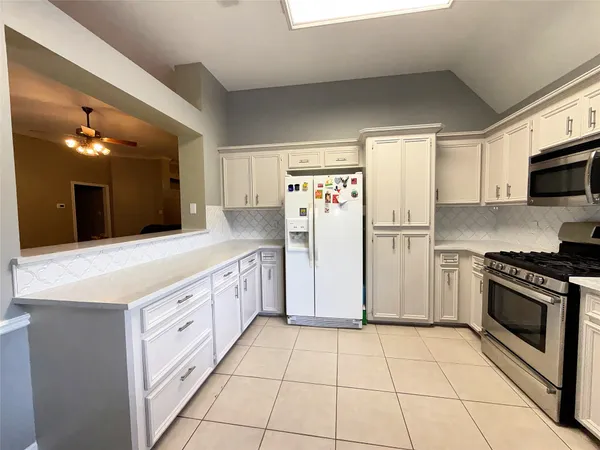 a large kitchen with a stove a sink dishwasher a refrigerator and a oven with wooden floor