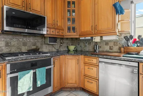 a kitchen with stainless steel appliances granite countertop a stove top oven a sink dishwasher and microwave with wooden floor