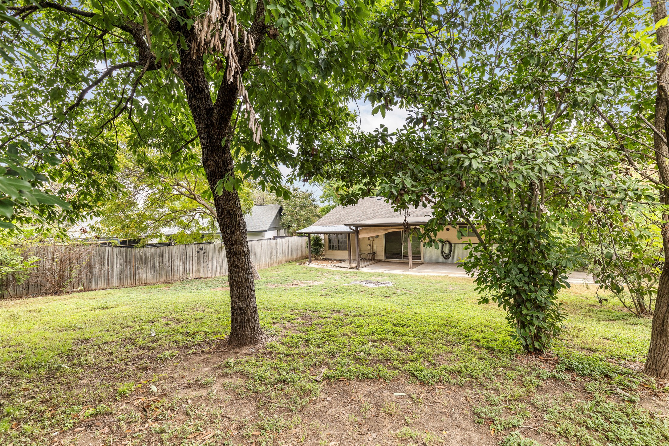 7506 Glenhill Road Austin, TX 78752 - Photo 23 of 24 Backyard with mature trees and a covered patio offers a private outdoor retreat.