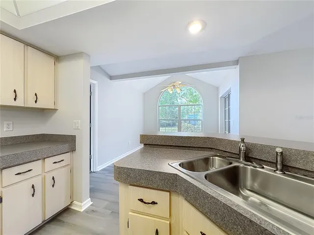 an empty room with a chandelier fan and windows