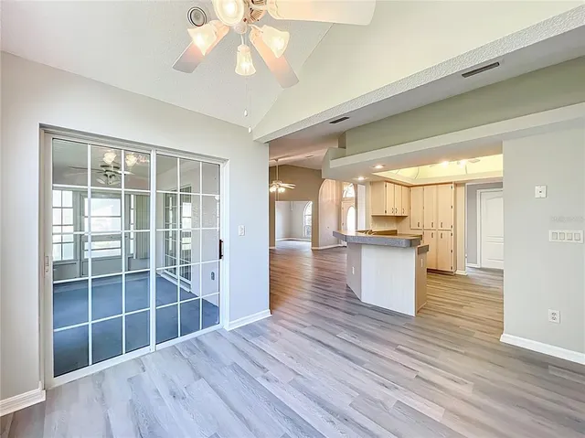 an empty room with windows and chandelier fan