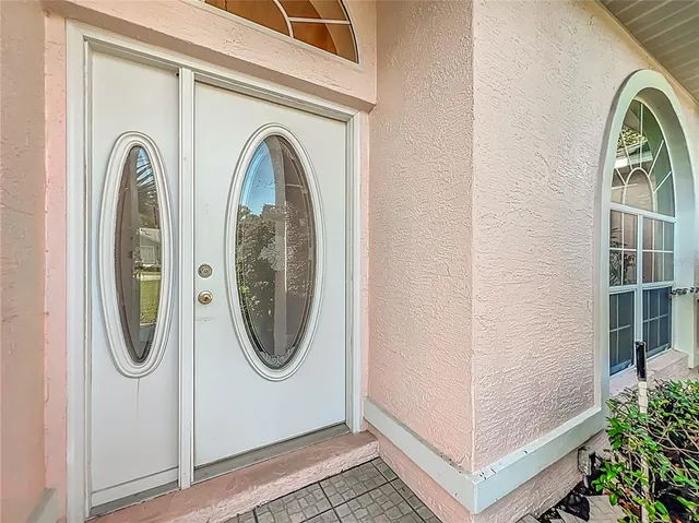 an empty room with wooden floor chandelier fan and windows