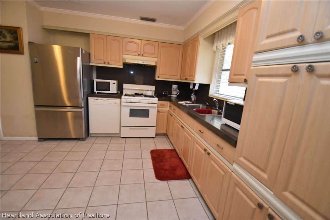 3906 Lakewood Road Sebring, FL 33875 - Photo 4 of 18 a kitchen with white cabinets and white appliances