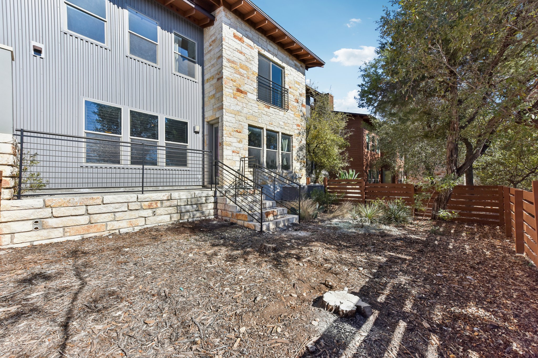 8110 Ranch Road 2222, Unit 98 Austin, TX 78730 - Photo 32 of 37 Rear view of property with stone siding, a fenced backyard, and board and batten siding