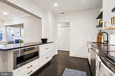 a kitchen with stainless steel appliances wooden floor sink and wooden cabinets