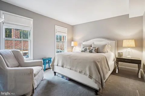 a bedroom with a bed a couch and windows