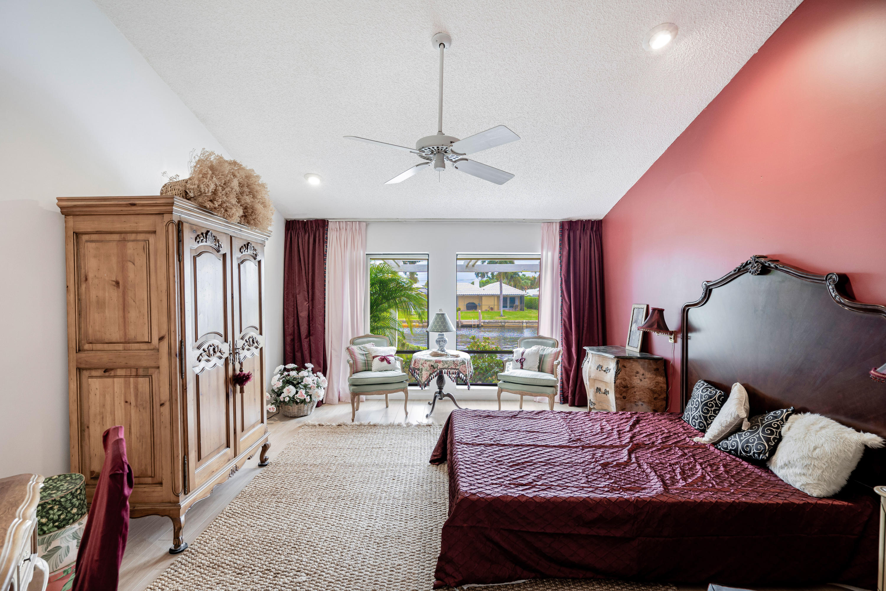 861 Camino Gardens Lane Boca Raton, FL 33432 - Photo 21 of 37 a bedroom with a bed a chandelier and a flat screen tv