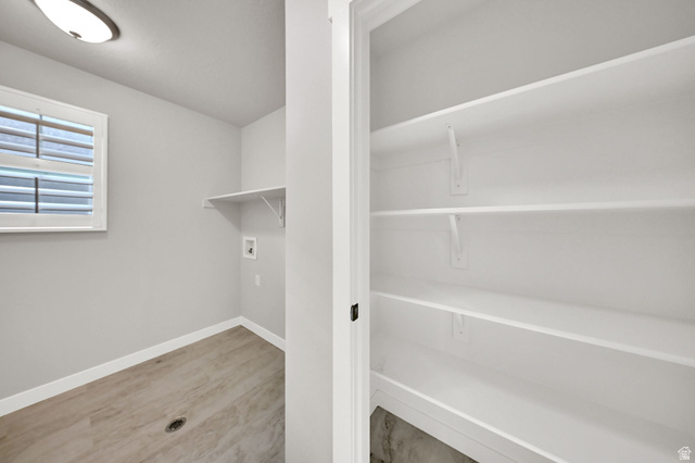 7817 West Kings Top Road Magna, UT 84044 - Photo 24 of 29 Laundry area with wood-finish flooring, a window with horizontal blinds, and a built-in shelf