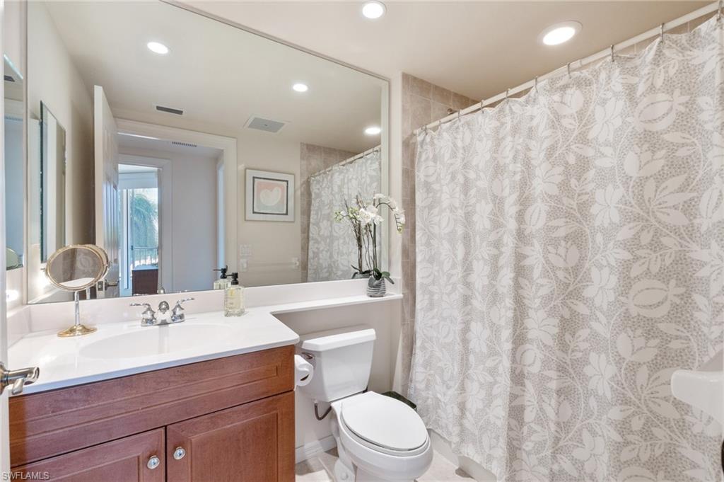 1065 Borghese Lane, Unit 203 Naples, FL 34114 - Photo 14 of 24 a bathroom with a toilet a sink and a mirror