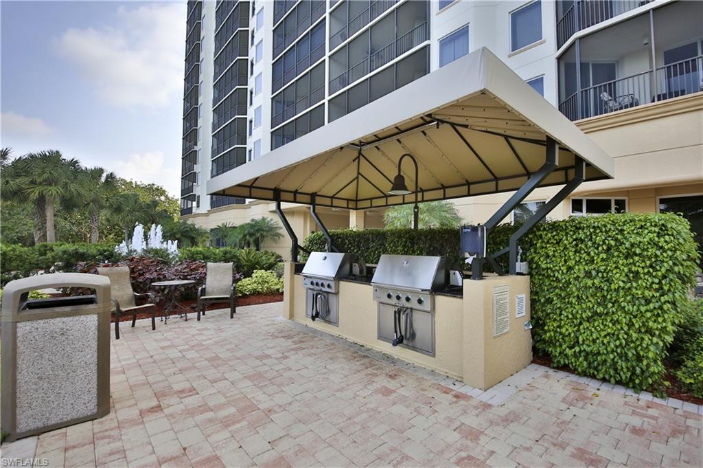 1065 Borghese Lane, Unit 203 Naples, FL 34114 - Photo 23 of 24 a view of a patio with table and chairs under an umbrella